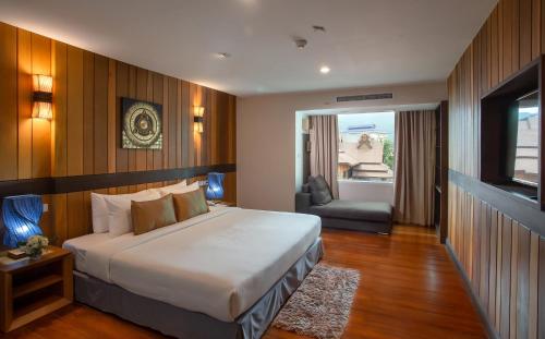 ein Schlafzimmer mit einem Bett und einem Stuhl in einem Zimmer in der Unterkunft Khum Phucome Hotel -SHA Extra Plus in Chiang Mai