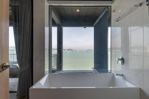 a bathroom with a tub with a view of the ocean at Arch39 Phuket Beach Front - SHA Plus in Chalong 