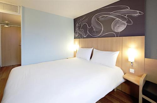 a bedroom with a large white bed and a painting on the wall at Ibis Barcelona Meridiana in Barcelona