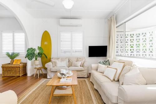 a living room with a white couch and a surfboard at Bungalow105 in Byron Bay