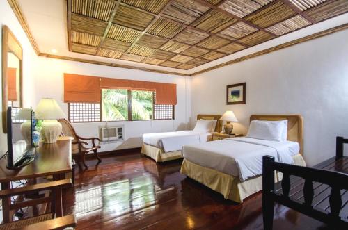 1 dormitorio con 2 camas, mesa y TV en Sea Wind Resort en Boracay