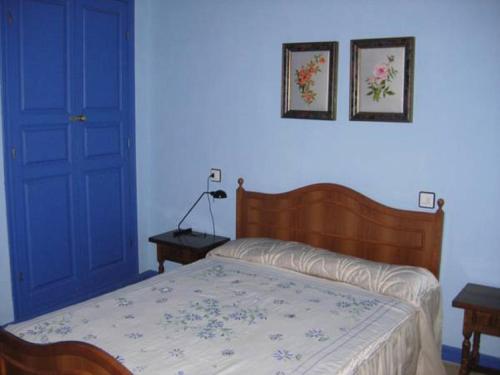 a bedroom with a bed and a blue door at Casa Rural El Cubano in La Fregeneda