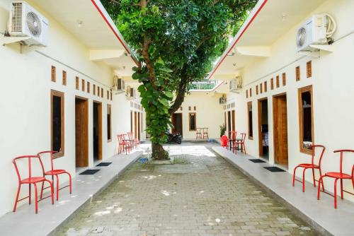 a courtyard of a building with red chairs and a tree at RedDoorz @ Umbul Ponggok Waterpark Klaten in Klaten