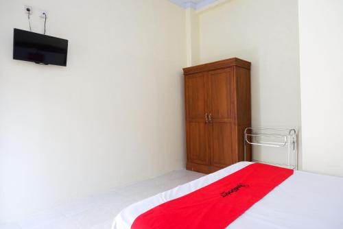 a bedroom with a bed and a dresser with a red blanket at RedDoorz @ Umbul Ponggok Waterpark Klaten in Klaten