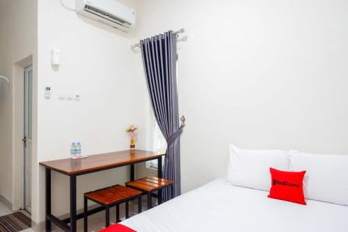 a room with a bed and a table with a desk at RedDoorz Syariah near RS Mitra Keluarga Tegal in Tegal