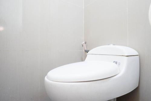 a white toilet in a bathroom with a white wall at RedDoorz Syariah near RS Mitra Keluarga Tegal in Tegal