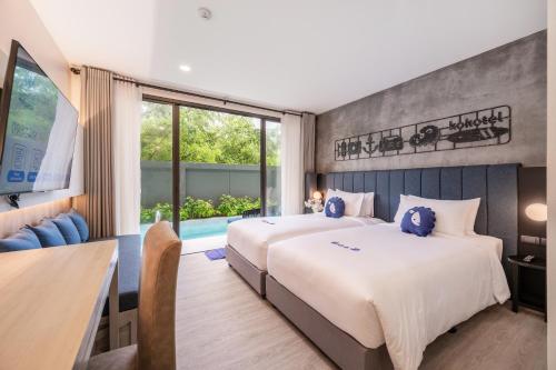 Cette chambre comprend 2 lits et une table. dans l'établissement Kokotel Phuket Nai Yang Beach - SHA Extra Plus, à Nai Yang Beach