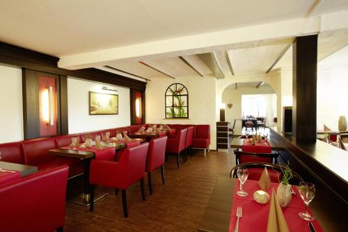 un restaurante con sillas rojas y mesas con copas de vino en Hotel Altastenberg, en Winterberg