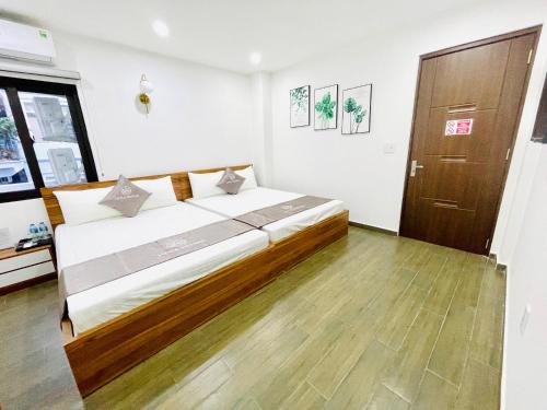 een slaapkamer met een groot bed en een houten vloer bij Little Vietnam Hotel - Cát Bà in Cat Ba