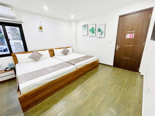 a bedroom with a large bed and a wooden floor at Little Vietnam Hotel - Cát Bà in Cat Ba
