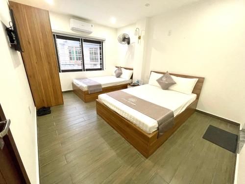 a hotel room with two beds and a window at Little Vietnam Hotel - Cát Bà in Cat Ba