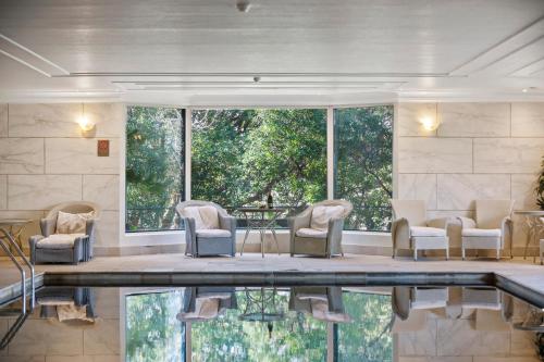 a room with a pool with chairs and a table at Lilianfels Blue Mountains Resort & Spa in Katoomba