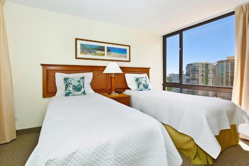 a bedroom with two beds and a large window at Waikiki Sunset #1414 in Honolulu