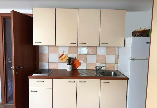 a kitchen with white cabinets and a sink at Apartments Azur - 10 m from sea in Ilovik