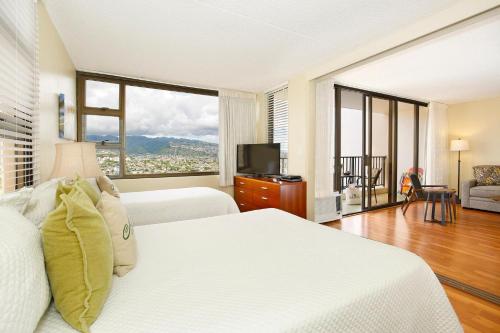 a bedroom with a white bed and a large window at Waikiki Banyan #2601-T2 in Honolulu