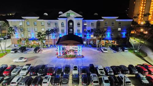 a parking lot with cars parked in front of a building at Holiday Inn Express Hotel and Suites South Padre Island by IHG in South Padre Island