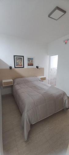 - un lit dans une chambre blanche avec 2 photos sur le mur dans l'établissement "MANTRA APART" y RENT CAR, à La Rioja