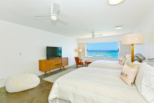 a bedroom with two beds and a flat screen tv at Colony Surf #604 in Honolulu