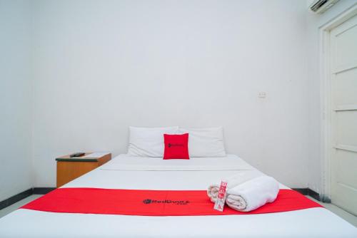 a bed with a red pillow and towels on it at RedDoorz near Rumah Sakit Baptis Kediri in Kediri