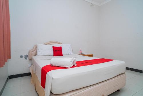 a white bed with red pillows on it in a room at RedDoorz near Rumah Sakit Baptis Kediri in Kediri