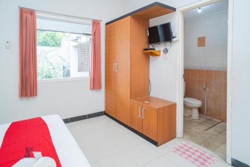 a bathroom with a bed and a toilet and a window at RedDoorz near Rumah Sakit Baptis Kediri in Kediri