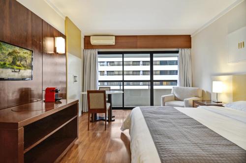a hotel room with a bed and a desk at Suite at the Grand Plaza Avenida Paulista in Sao Paulo
