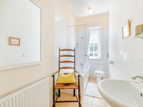 a bathroom with a chair with a yellow pillow on it at Woodlands By The Sea Cottage in Deal