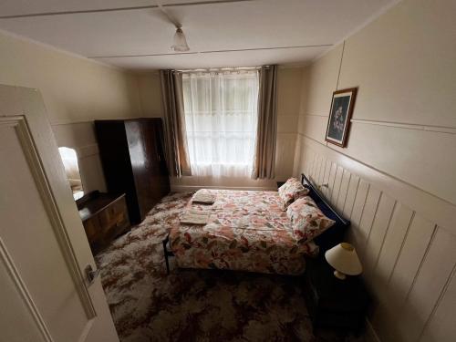 a small bedroom with a bed and a window at The Crooked Cottage in Murtoa