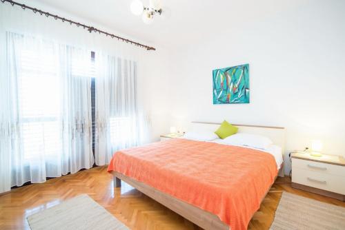 ein weißes Schlafzimmer mit einem Bett mit einer orangefarbenen Decke in der Unterkunft Apartments with a parking space Supetar, Brac - 18825 in Supetar
