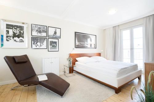 ein weißes Schlafzimmer mit einem Bett und einem Stuhl in der Unterkunft Haus Traavmünn in Travemünde