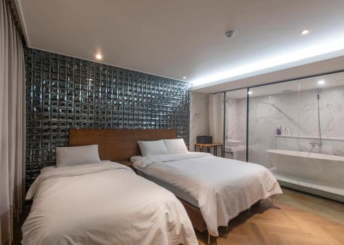 two beds in a bedroom with a tub and a sink at Hotel Wolmido in Incheon