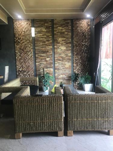 a lobby with wicker chairs and a brick wall at D'Rus Hill munduk in Singaraja