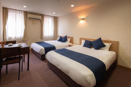 a hotel room with two beds and a table and a desk at Hotel Teiregikan in Tobe
