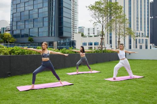 a group of women doing yoga in the grass at lyf Sukhumvit 8 Bangkok in Bangkok