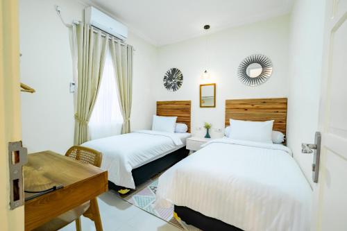 1 dormitorio con 2 camas y espejo en Siji Plemburan Vacation Home en Kejayan