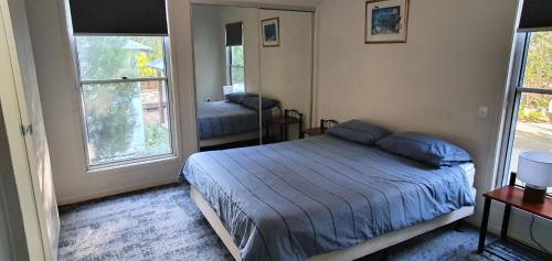 a bedroom with a bed and two windows at Shelleys House in Rainbow Beach