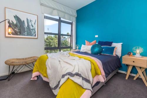 a blue bedroom with a bed and a window at Deluxe Mahuhu 2 BR - Spark Arena - FREE PARKING in Auckland