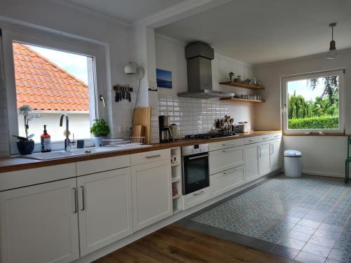 uma cozinha com armários brancos e uma grande janela em Haus Sonnenlicht. Idylle am Ratzeburger See! em Ratzeburg