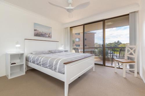 a white bedroom with a bed and a balcony at Pinnacle 202 in Forster