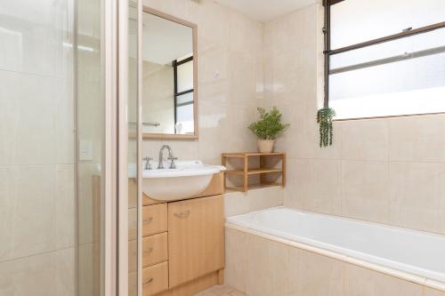 a bathroom with a tub and a sink and a mirror at Pinnacle 202 in Forster