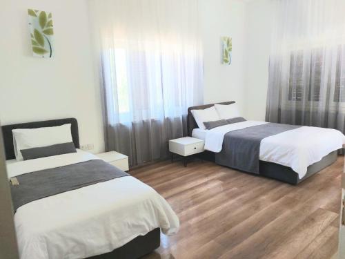 two beds in a room with wooden floors at Secret Garden Guest House 02 in Famagusta
