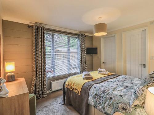 a bedroom with a bed and a large window at Daffodils Lodge in Bowness-on-Windermere