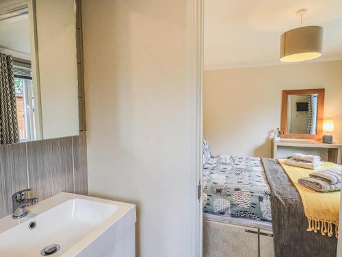 a bathroom with a sink and a bed at Daffodils Lodge in Bowness-on-Windermere