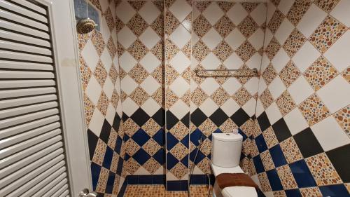 a bathroom with a toilet and a tiled wall at Vech Guesthouse Patong in Patong Beach