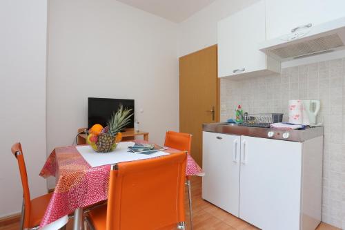a small kitchen with a table and a white refrigerator at Apartments by the sea Podgora, Makarska - 18918 in Podgora