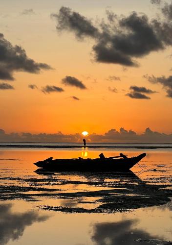 a man standing on a boat on the beach at sunset at The View of Zanzibar in Michamvi