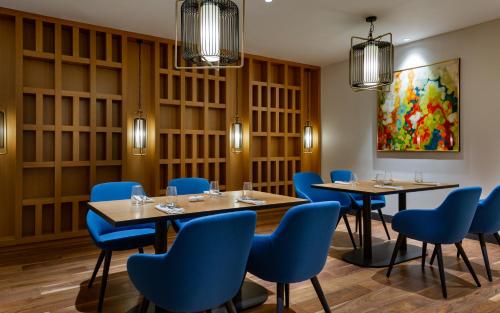 a dining room with tables and blue chairs at Swissôtel Wellness Resort Alatau Almaty in Almaty