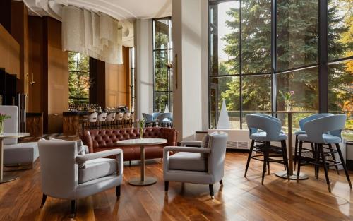 a lobby with chairs and tables and windows at Swissôtel Wellness Resort Alatau Almaty in Almaty