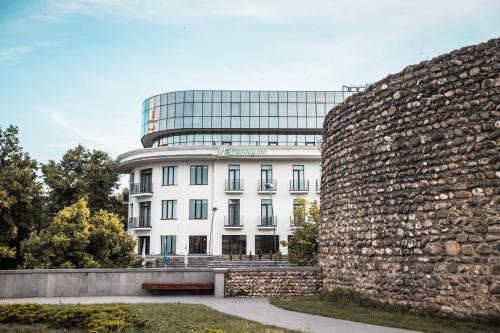 a building in front of a stone wall at Holiday Inn Telavi by IHG in Tʼelavi