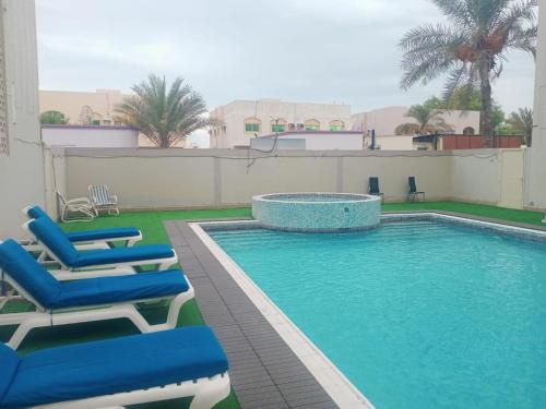 basen z leżakami obok budynku w obiekcie Oasis Hotel Apartment w mieście Ras al-Chajma